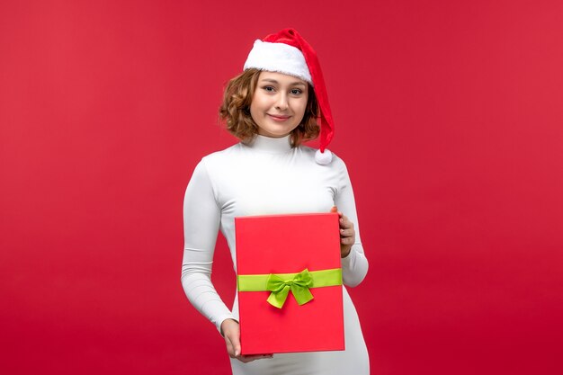 Vooraanzicht van jonge vrouw met kerstcadeau op rood