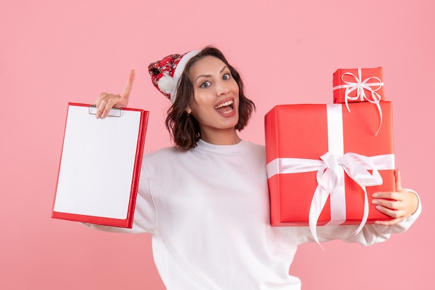 Vooraanzicht van jonge vrouw met kerstcadeautjes op de roze muur