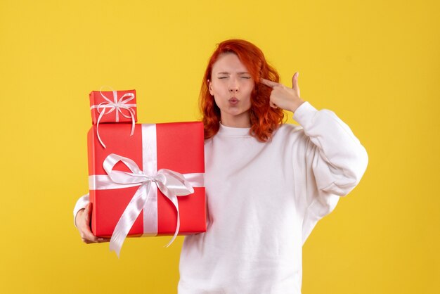 Vooraanzicht van jonge vrouw met kerstcadeautjes op gele muur