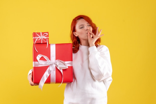 Vooraanzicht van jonge vrouw met kerstcadeautjes op gele muur