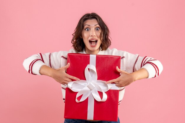 Vooraanzicht van jonge vrouw met Kerstmis aanwezig op de roze muur