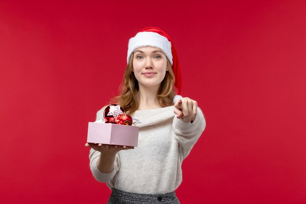 Vooraanzicht van jonge vrouw met kerstspeelgoed op rood