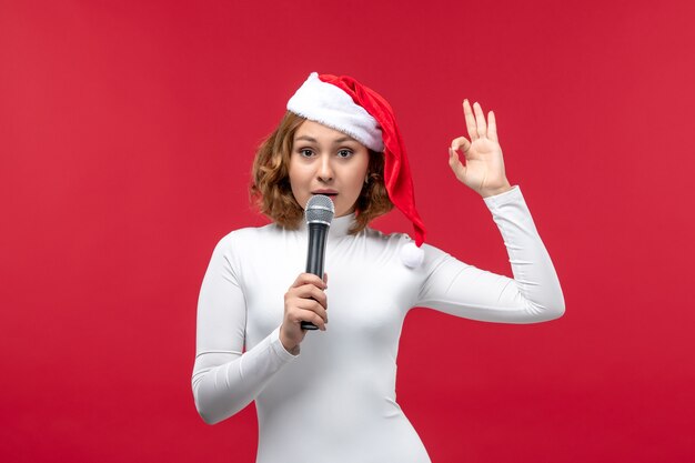 Vooraanzicht van jonge vrouw met microfoon op rood