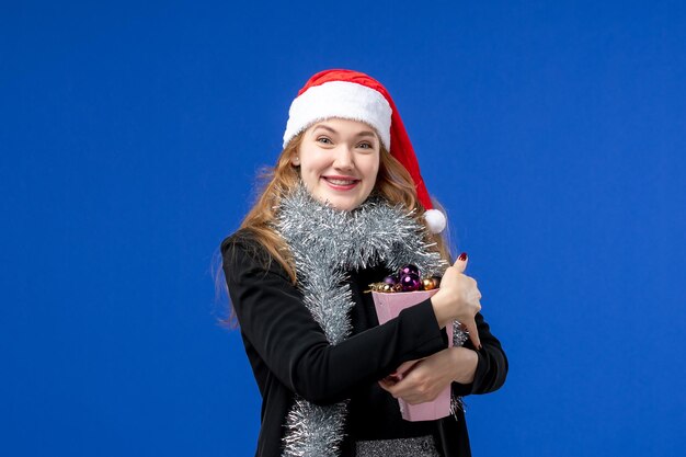 Vooraanzicht van jonge vrouw met nieuwjaarsboomspeelgoed op blauwe muur