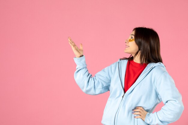 vooraanzicht van jonge vrouw met ooglapjes onder haar ogen op roze muur