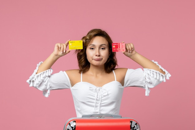 Vooraanzicht van jonge vrouw met vakantietas met bankkaarten op de roze muur pink