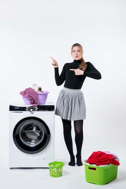 Gratis foto vooraanzicht van jonge vrouw met wasmachine en vuile kleren op witte muur