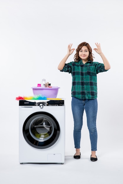 Vooraanzicht van jonge vrouw met wasmachine op witte muur