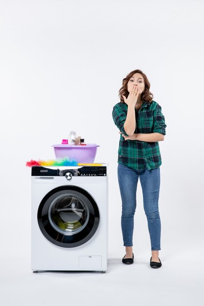 Vooraanzicht van jonge vrouw met wasmachine op witte muur