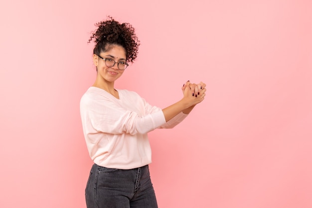 Gratis foto vooraanzicht van jonge vrouw opgetogen op roze muur