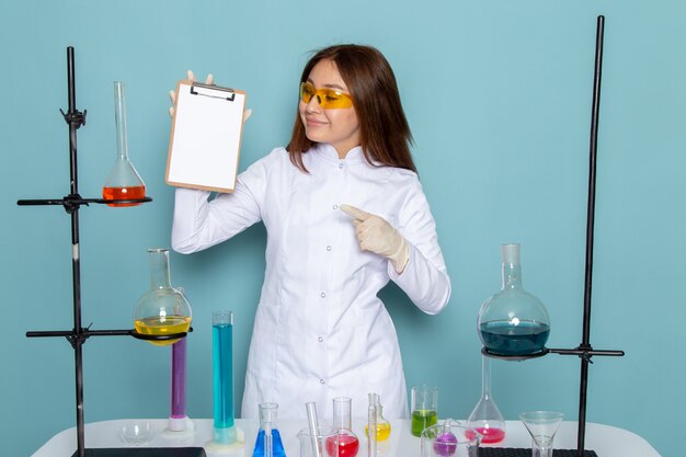 Vooraanzicht van jonge vrouwelijke chemicus in wit kostuum voor de blocnote van de lijstholding whtie