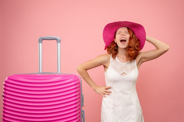 Vooraanzicht van jonge vrouwelijke toerist met roze hoed en zak op roze muur