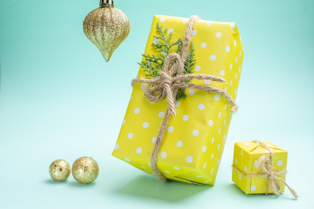 Vooraanzicht van kerstachtergrond met gele geschenkdozen en decoratieaccessoires op pastelgroene achtergrond
