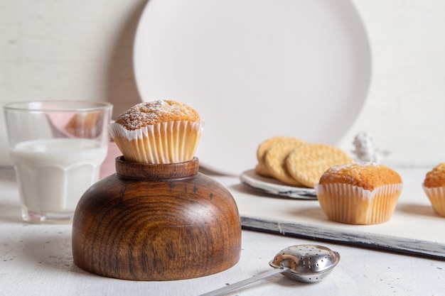 Vooraanzicht van kleine lekkere taarten met suiker poeder melk en koekjes op de witte ondergrond