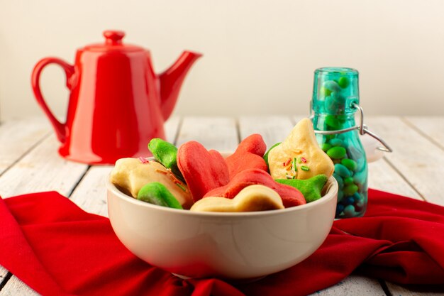 Vooraanzicht van kleurrijke heerlijke koekjes verschillend gevormde binnenplaat met rode ketel