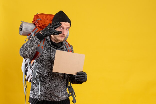 Vooraanzicht van knappe mannelijke camper met lederen handschoenen en rugzak met leeg karton