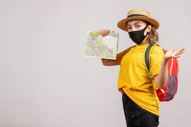 Vooraanzicht van koele vrouwelijke reiziger met de zwarte kaart van de maskerholding op witte muur