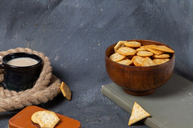 Vooraanzicht van kopje melk met chips en crackers op het grijze oppervlak