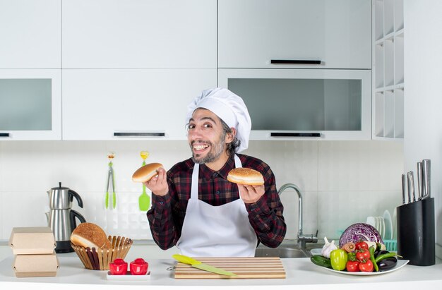 Vooraanzicht van lachende mannelijke chef-kok met brood in de keuken