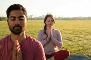 Gratis foto vooraanzicht van man en vrouw die buiten mediteren op yogamatten
