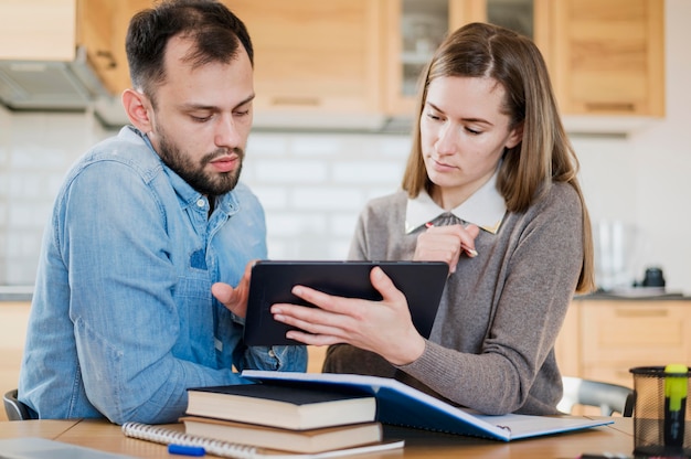 Gratis foto vooraanzicht van man en vrouw die thuis van tablet leren