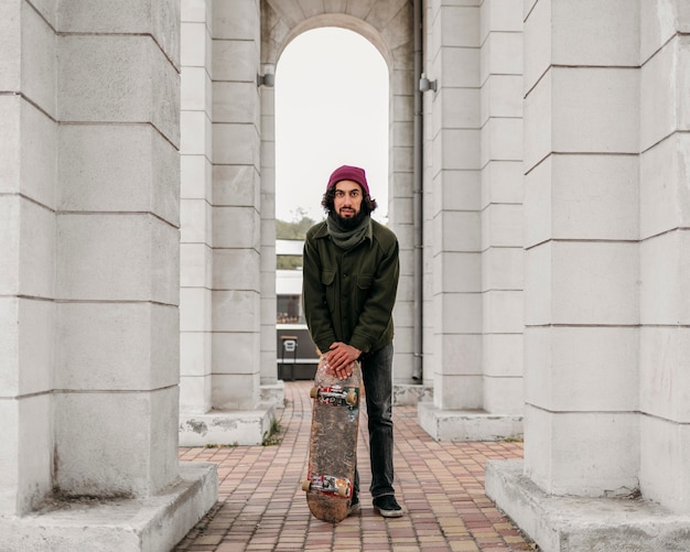 Vooraanzicht van man poseren met zijn skateboard in de stad