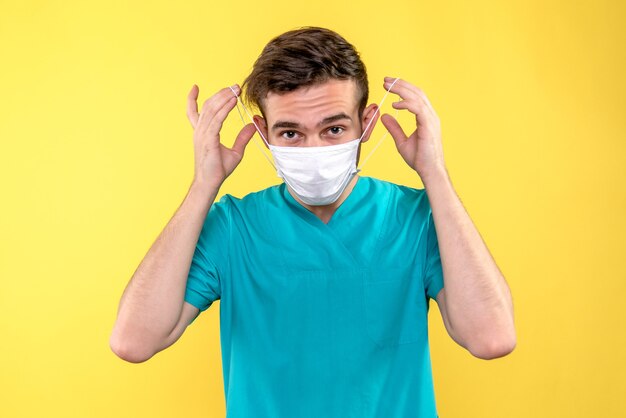 Vooraanzicht van mannelijke arts die masker op gele muur draagt