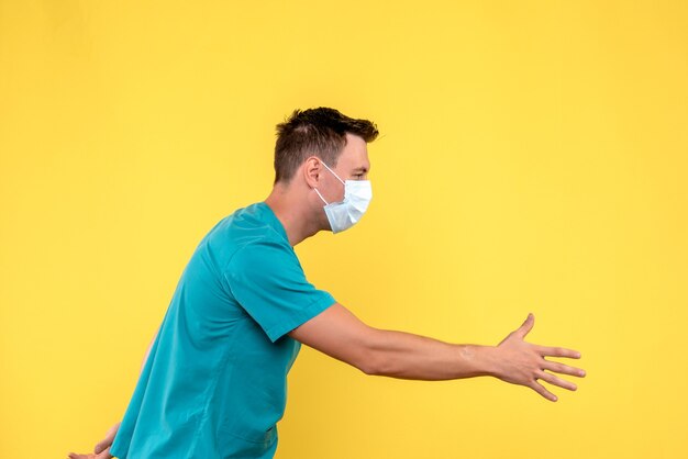 Vooraanzicht van mannelijke arts handen schudden met iemand op gele muur