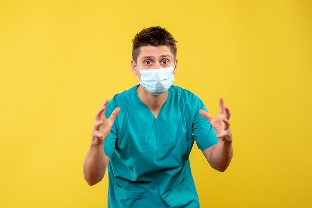 Vooraanzicht van mannelijke arts in beschermend masker op gele muur