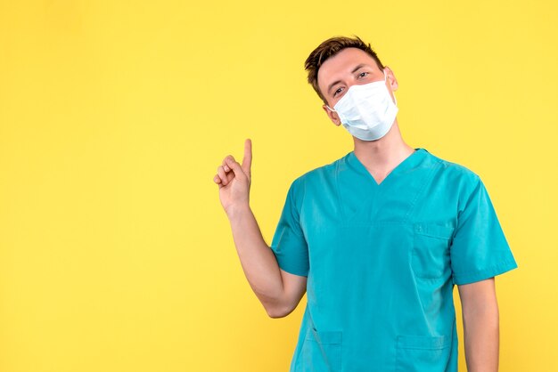 Vooraanzicht van mannelijke arts in masker op gele muur
