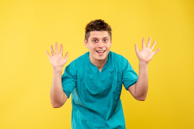 Vooraanzicht van mannelijke arts in medisch kostuum op gele muur