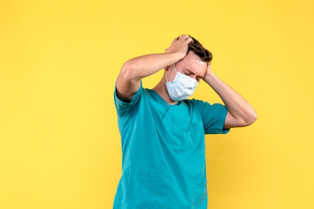 Vooraanzicht van mannelijke arts met ernstige hoofdpijn op gele muur