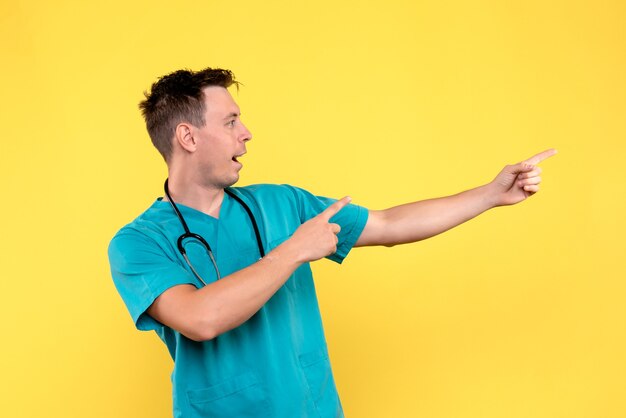 Vooraanzicht van mannelijke arts met opgewonden uitdrukking op gele muur