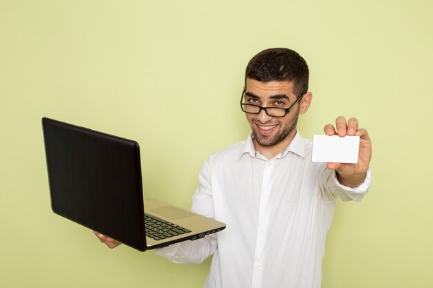 Vooraanzicht van mannelijke beambte in wit overhemd met witte kaart en laptop op de groene muur