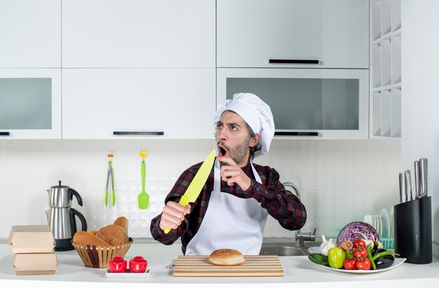 Vooraanzicht van mannelijke chef-kok wijzend op mes in de keuken