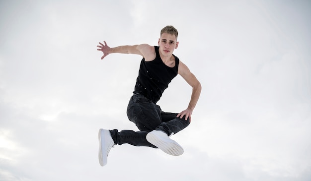 Gratis foto vooraanzicht van mannelijke danser die terwijl in de lucht stelt