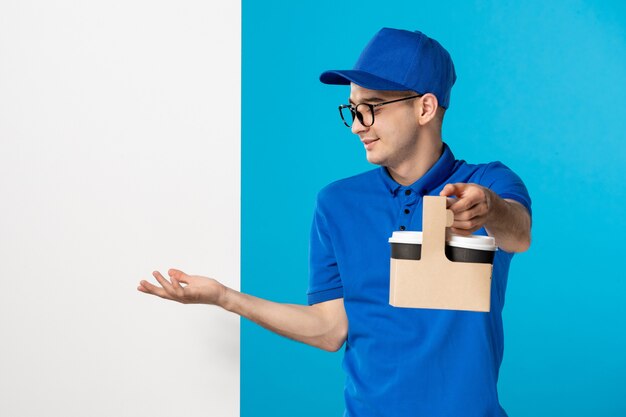 Vooraanzicht van mannelijke koerier in blauw uniform met koffie op het blauw