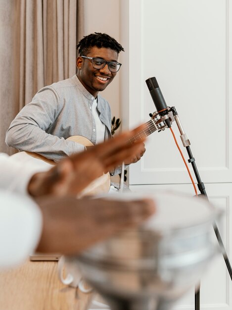 Vooraanzicht van mannelijke muzikant thuis gitaar spelen en zingen