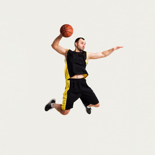 Gratis foto vooraanzicht van mannelijke speler die midden in de lucht stellen terwijl het werpen van basketbal