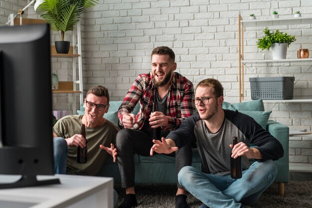 Vooraanzicht van mannelijke vrienden die samen op tv naar sport kijken
