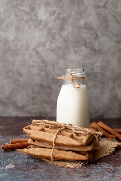 Vooraanzicht van melkfles en kaneelstokjes met verpakte wafels