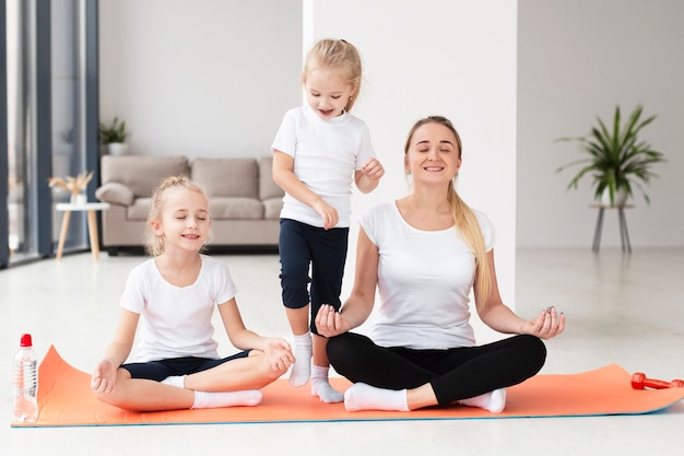Gratis foto vooraanzicht van moeder en dochters die yoga thuis uitoefenen