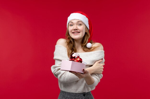 Vooraanzicht van mooie vrouw met kerstspeelgoed op rood