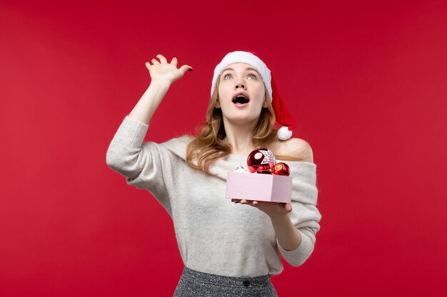 Vooraanzicht van mooie vrouw met kerstspeelgoed op rood