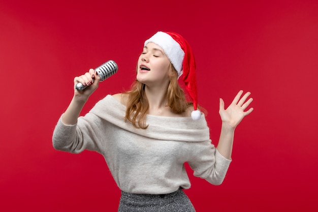 Vooraanzicht van mooie vrouwelijke zang met microfoon op rood