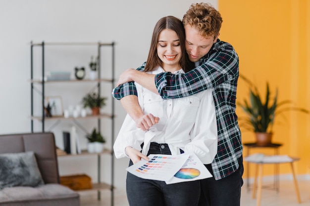 Vooraanzicht van omhelsd paar dat samen van plan is om het huis opnieuw in te richten