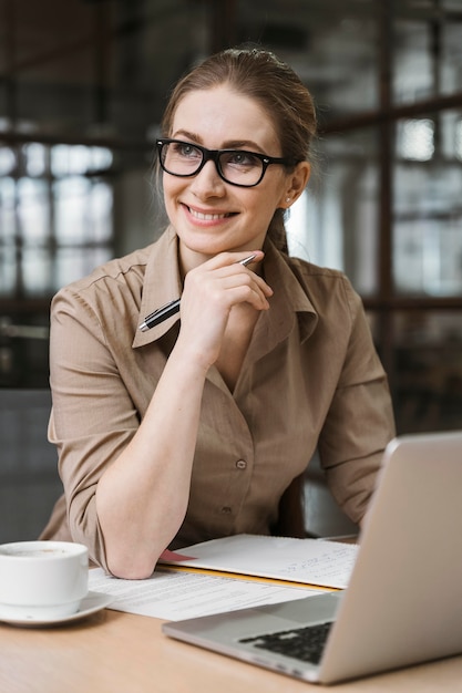 Vooraanzicht van onderneemster die met laptop bij bureau werkt