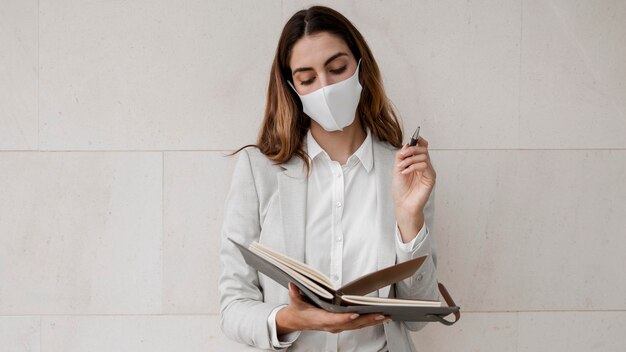 Gratis foto vooraanzicht van onderneemster met masker en agenda