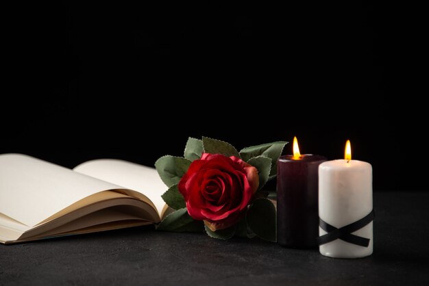 Vooraanzicht van open boek met kaarsen en roos op zwart
