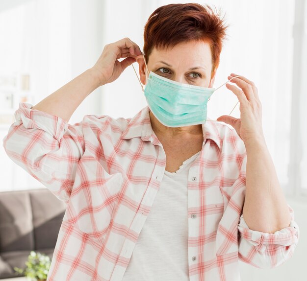 Vooraanzicht van oudere vrouw die op medisch masker zet